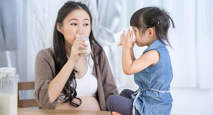 Mom and daughter drink milk at home