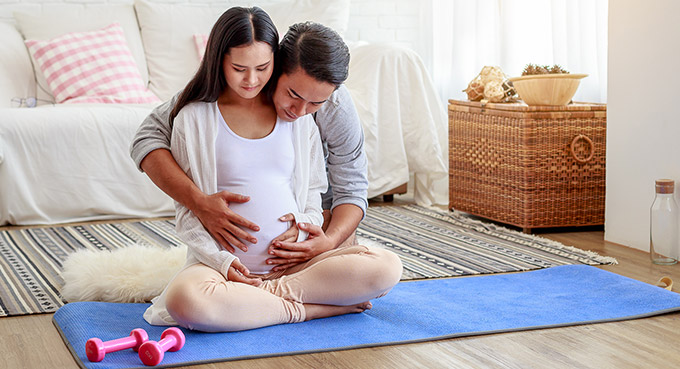 pregnant wife and husband on yoga mat