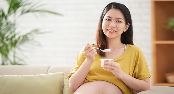 Pregnant woman eating yoghurt.