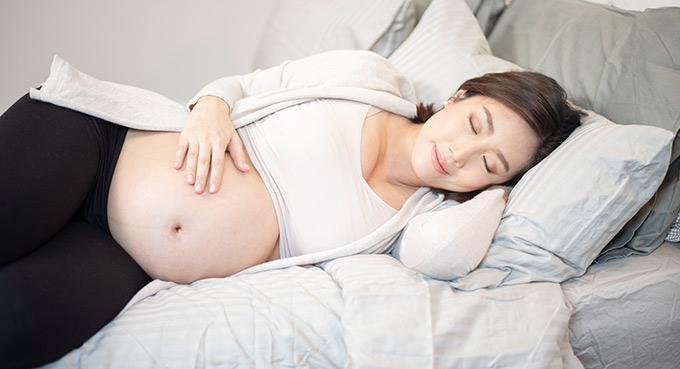 Pregnant woman relaxing and sleeping on bed