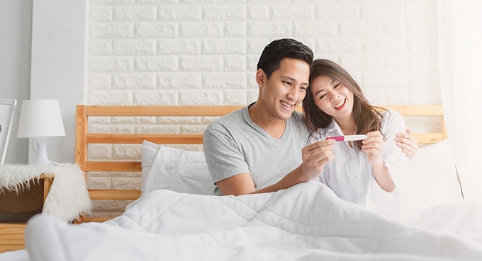 Happy couple smiling after checking pregnancy test
