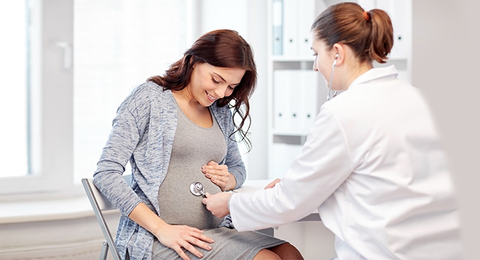 Doctor checking pregnant woman’s tummy
