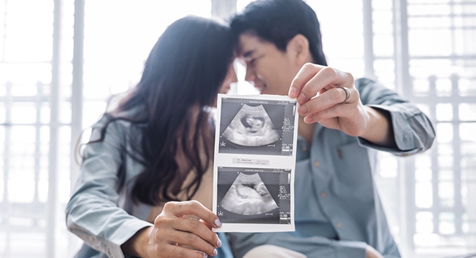 Pregnant woman and her husband holding ultrasound picture
