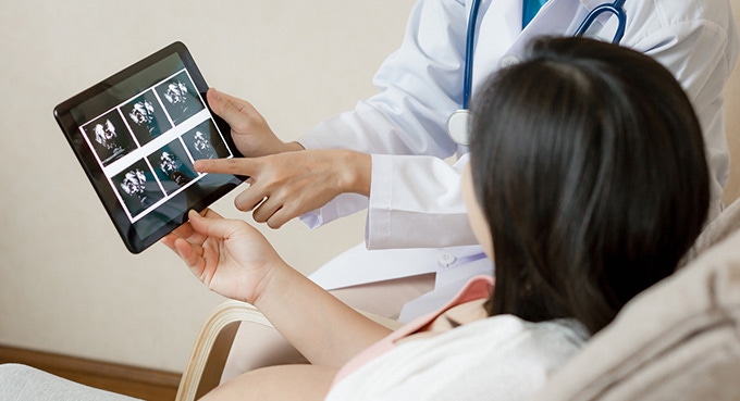 Pregnant woman and doctor are watching ultrasound photo