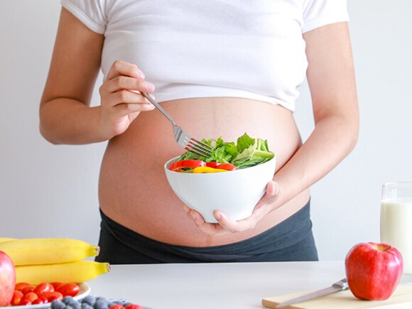 pregnant woman eats vegetable salad and fruit