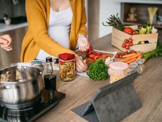 pregnant woman cooks healthy food