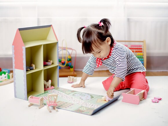 Baby girl playing doll house at home