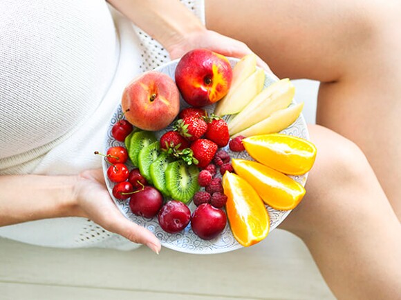 pregnant woman holding fruit plate